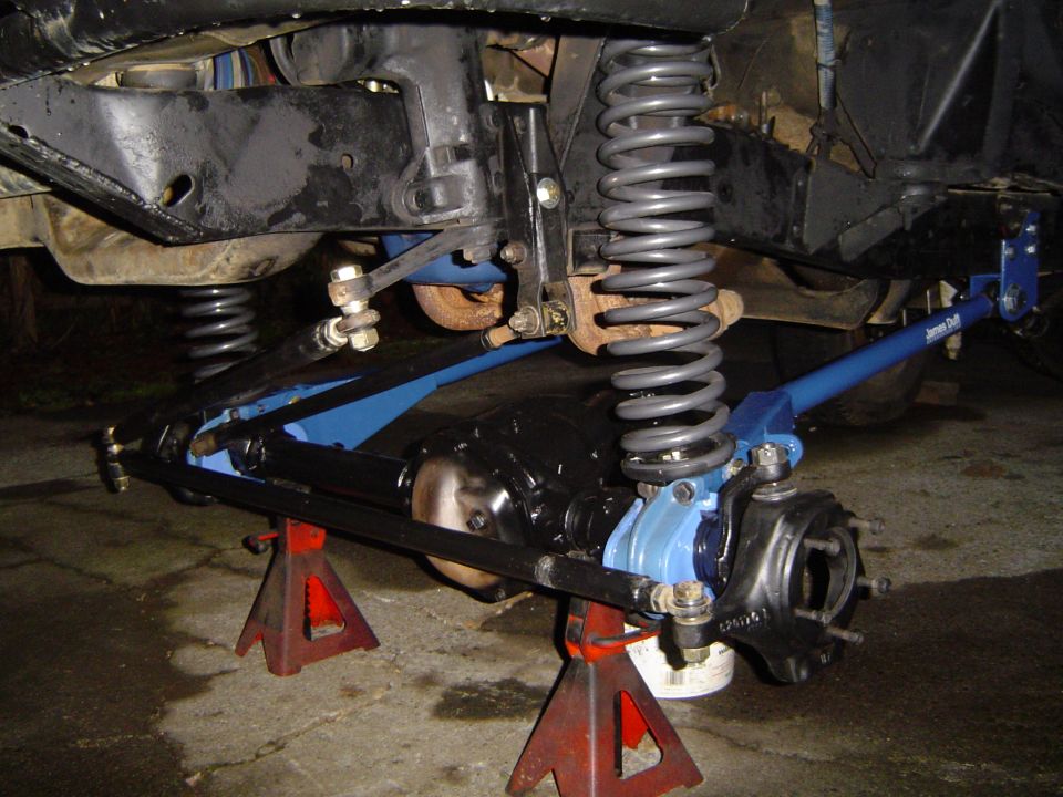 Vehicle suspension with blue control arms and grey coil springs on jack stands