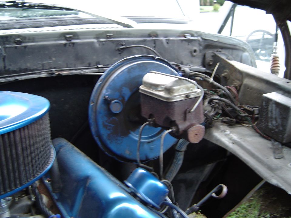 Blue brake booster and master cylinder on the firewall of a truck engine bay