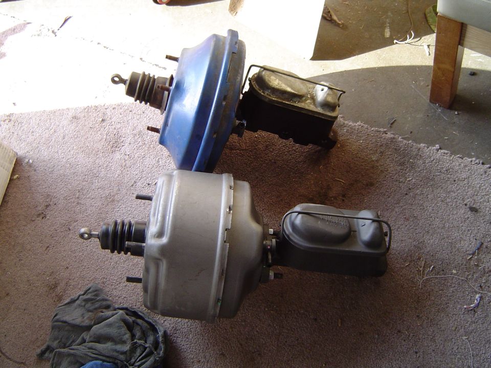 Two automotive brake boosters with attached master cylinders, one blue and one silver