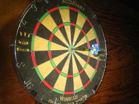1968 Ford Mustang - A dart is stuck in the center of a dartboard, which is mounted on a wooden surface.