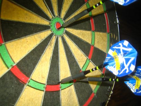 1968 Ford Mustang - A close-up view of a dartboard with several darts embedded in it, including one in the bullseye.
