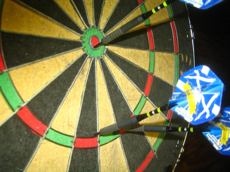 Dartboard with three darts in the bullseye and surrounding segments