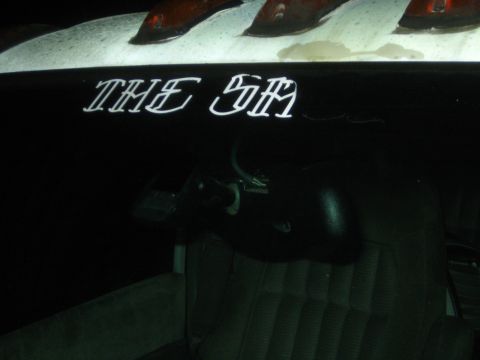 1990 Ford Bronco - dark interior panel or tailgate airbrushed with white script reading THE SM, with cloth seats visible below.