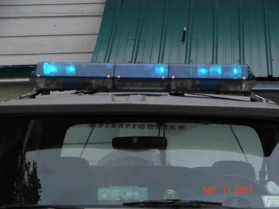 Emergency light bar with blue lights on top of a vehicle, "FIREFIGHTERS" text on rear window