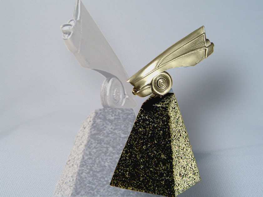 Brass sculpture of a 1957 Chevy tail fin and wheel mounted on a granite pyramid base