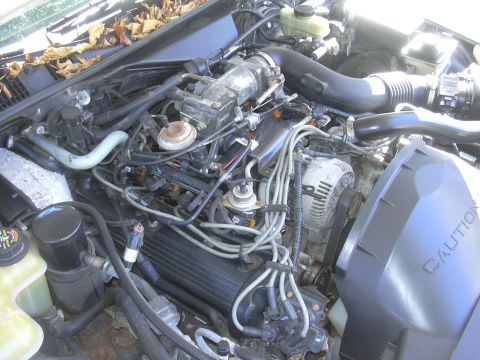 1997 Ford Crown Victoria - The engine bay of a vehicle, showing various components and a caution label on the fan shroud.