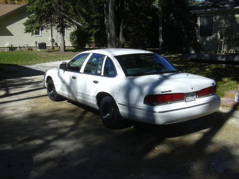 1997 Ford Crown Victoria - A white 1997 Ford Crown Victoria is parked in a driveway on a sunny day.