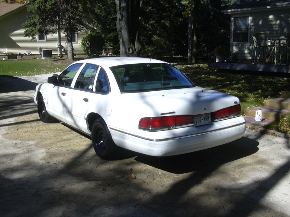 1997 Ford Crown Victoria, rear 3/4 view, white paint, black wheels, parked in driveway