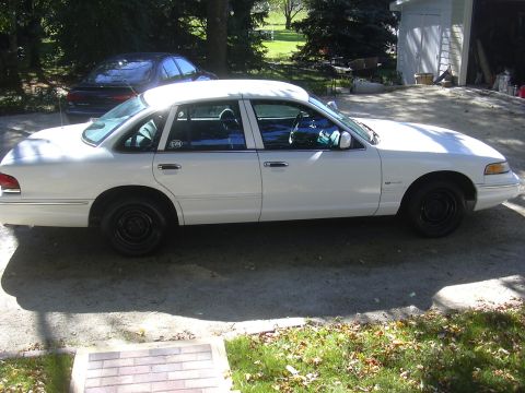1997 Ford Crown Victoria - A white 1997 Ford Crown Victoria is parked in a driveway with a dark sedan behind it.