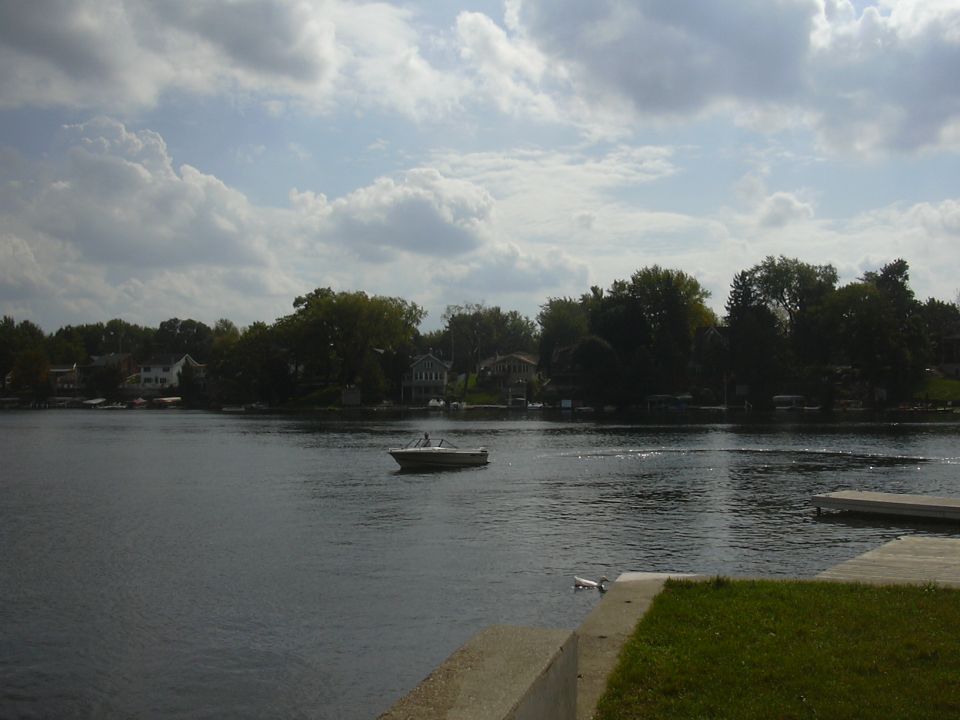Small white motorboat on a calm lake near a wooden dock