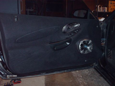 1995 Ford Probe - The interior door panel of a car features a custom speaker and decorative trim around the window controls.