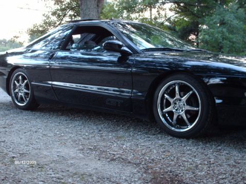 1995 Ford Probe - A black coupe, possibly a Ford Probe GT, is shown from the front three-quarter view with custom wheels.