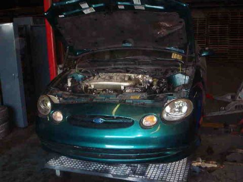 1993 Ford Taurus - Front view of a green Ford Taurus with its hood open, revealing the engine compartment.