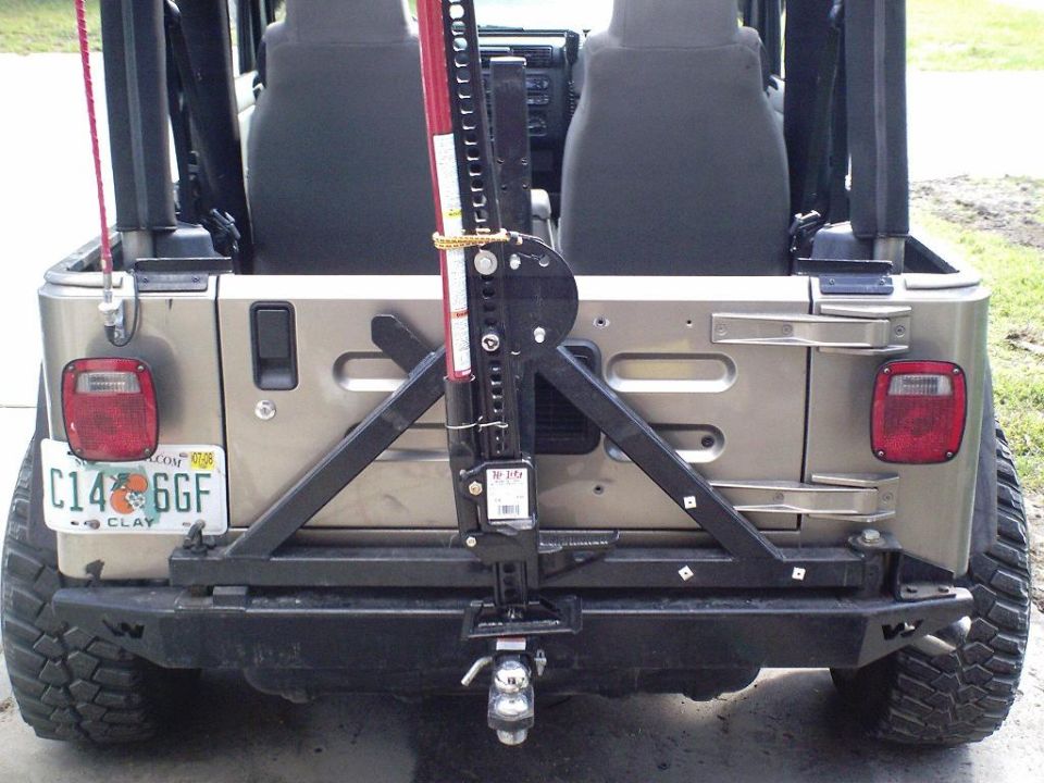 Tan Jeep's rear bumper with a Hi-Lift jack mounted on a spare tire carrier