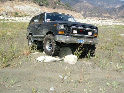 1981 Ford Bronco - This black SUV is shown off-roading over rocks and dirt in a dry, mountainous area.