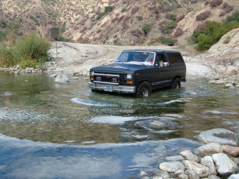 1981 Ford Bronco - This black Ford Bronco is navigating a rocky riverbed in a dry, mountainous area.