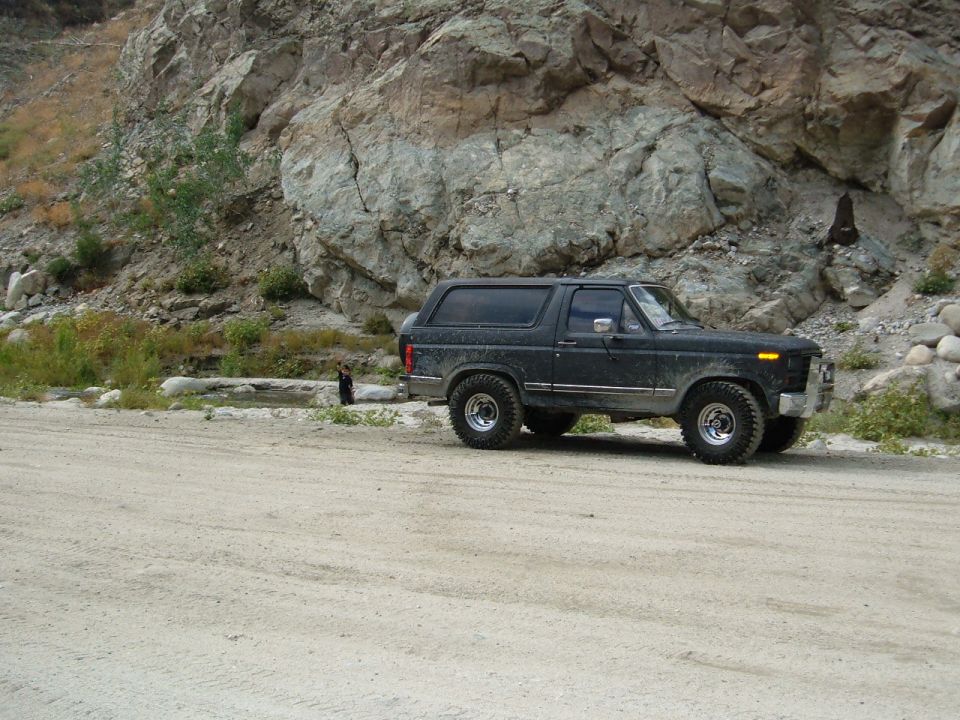1978 Ford Bronco parked on dirt road with rocky hillside behind it