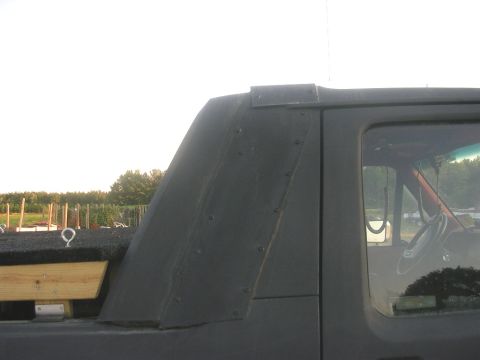 1989 Ford Bronco - Close-up view of the rear roofline and window of a dark SUV, with "SUPERMOTORS" visible at the bottom.