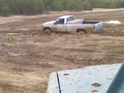 1989 Ford Bronco - A white pickup truck is stuck deep in the mud, with only its cab and part of the bed visible above the mire.