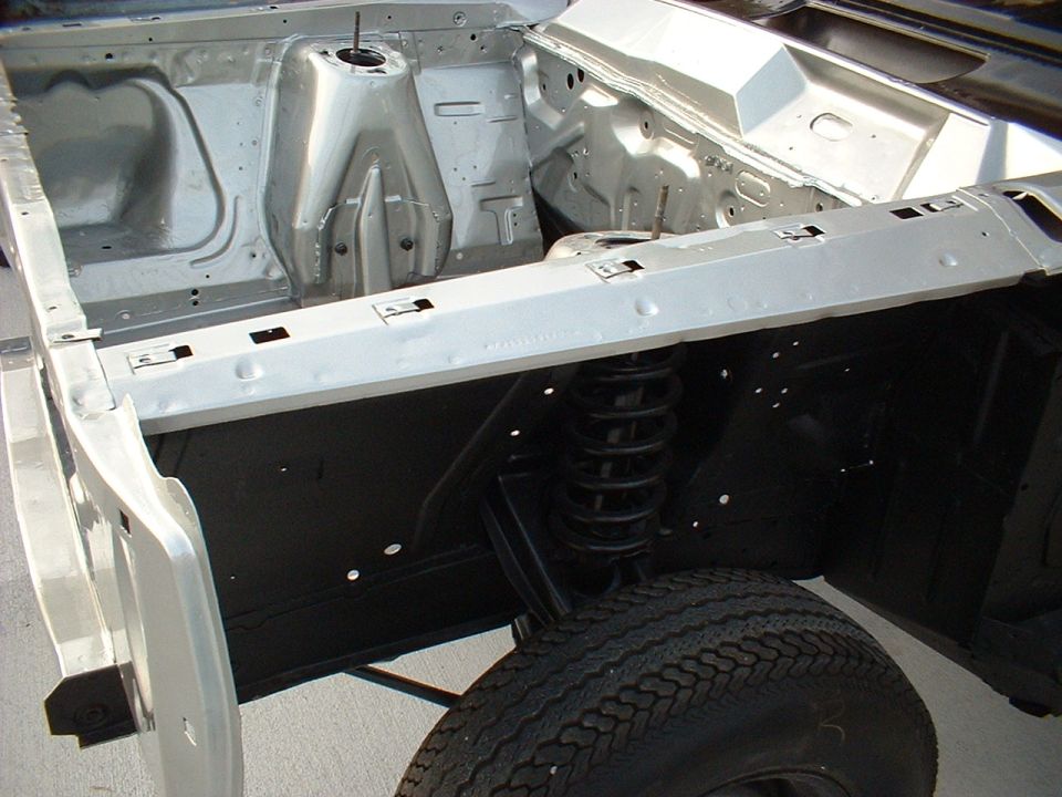 Restored bare engine bay with silver inner fenders, black shock tower and coil spring
