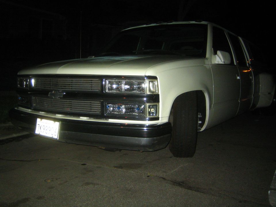 White dually pickup truck, front 3/4 view, lowered suspension, aftermarket headlights, license plate 7K98906