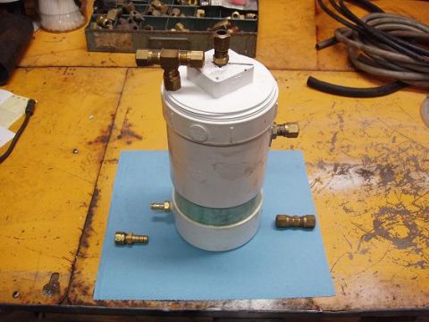 2001 Ford Excursion - Custom fuel filter or catch can assembly with brass fittings is shown on a workbench.