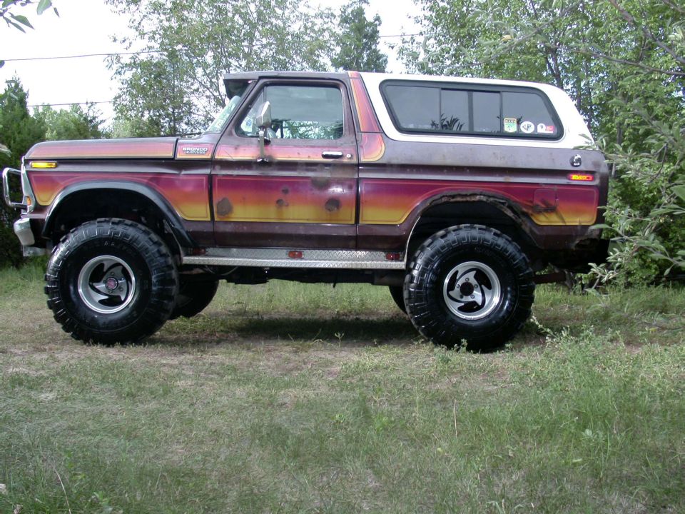 Side view of a lifted 1978 Ford Bronco with custom paint and off-road tires
