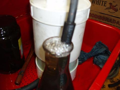 2001 Ford Excursion - A fluid transfer setup is shown, a bottle, a white cylinder, and a black hose with bubbles in the fluid.