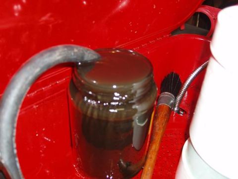 2001 Ford Excursion - A jar filled with dark fluid sits beside a brush in a red compartment.