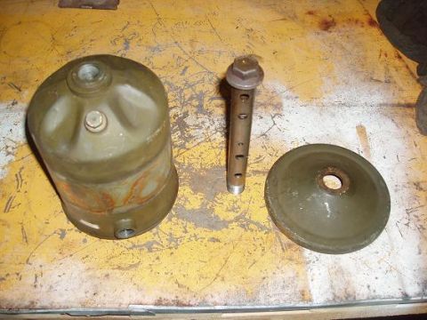 2001 Ford Excursion - Three automotive parts, possibly related to an oil filter system, are laid out on a workbench.