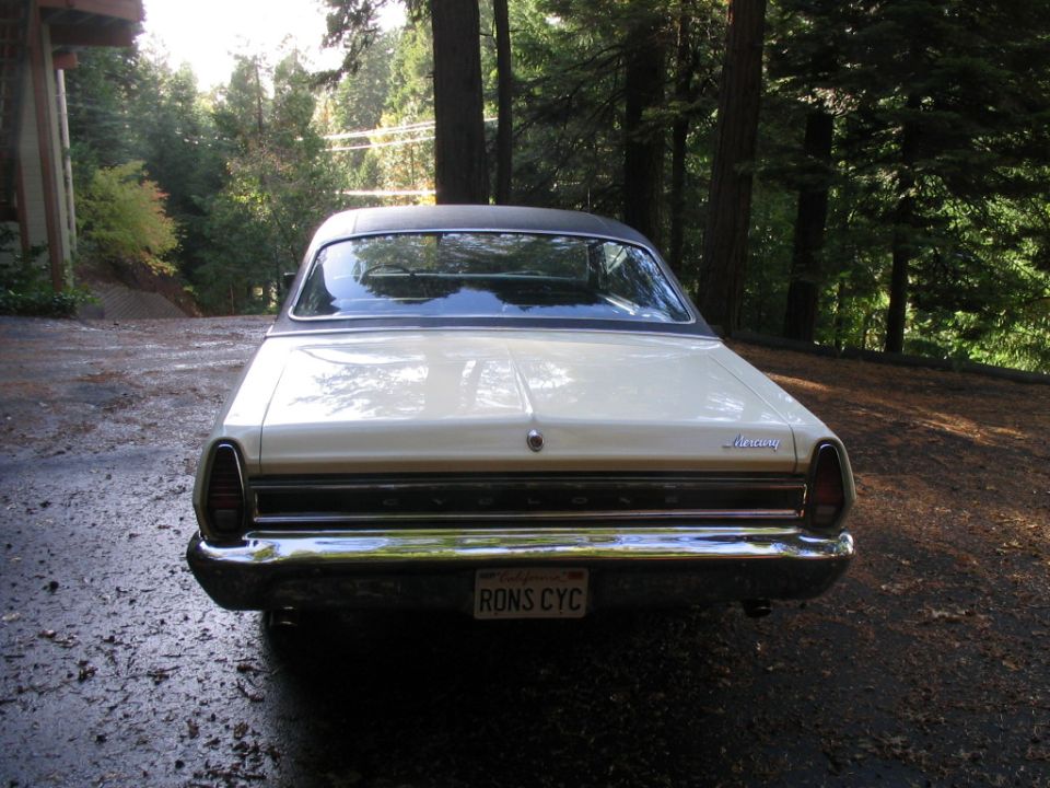Rear view of a cream-colored Mercury sedan with a black vinyl top. License plate reads RONS CYC