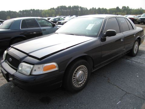 1991 Ford LTD Crown Victoria - This black Ford Crown Victoria is parked in a lot with other vehicles, its hood is open.