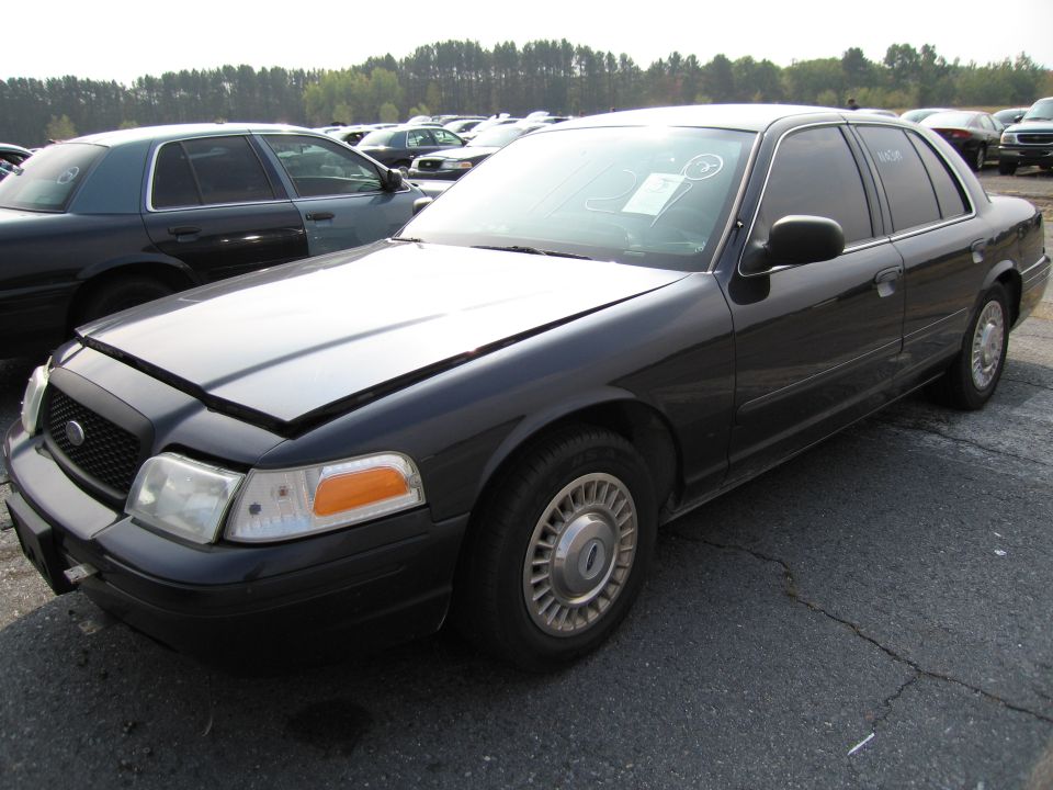 Black Ford Crown Victoria with hood up, parked in a lot with other cars