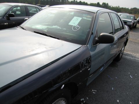 1991 Ford LTD Crown Victoria - A two-tone Ford Crown Victoria is parked in a lot with other vehicles. The fender has been painted a different color than the rest of the c…