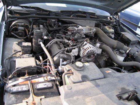 1991 Ford LTD Crown Victoria - The engine compartment of a car, showing the V8 engine and its various parts.