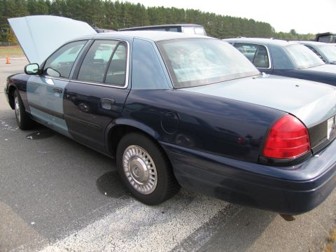 1991 Ford LTD Crown Victoria - A two-tone Ford Crown Victoria is parked with its hood up, alongside another similar vehicle.