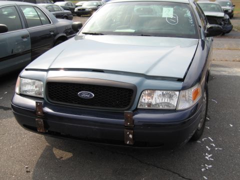 1991 Ford LTD Crown Victoria - A blue and light blue Ford Crown Victoria is parked in a lot with other vehicles. The front grille has a Ford logo.