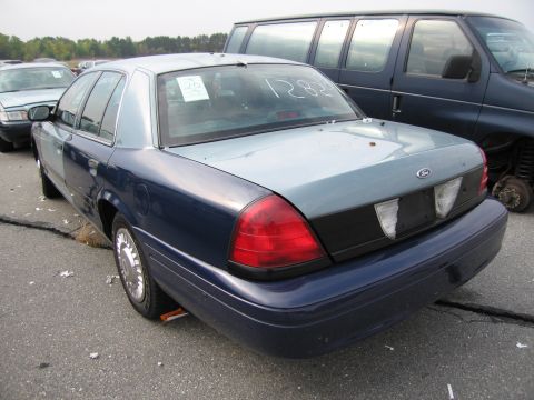 1991 Ford LTD Crown Victoria - A two-tone blue Ford Crown Victoria is parked in a lot next to a van, with visible markings on its rear window.