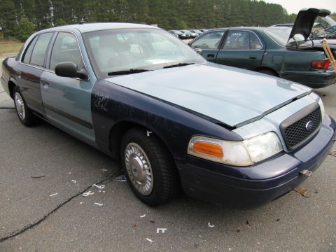 1991 Ford LTD Crown Victoria - A four-door sedan with a dark blue front bumper and fender, light blue hood, and blue-grey doors sits in a lot with other vehicles.