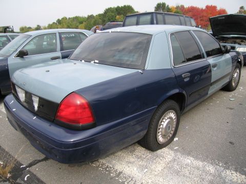 1991 Ford LTD Crown Victoria - A two-tone sedan with a flat tire sits in a lot next to other vehicles.