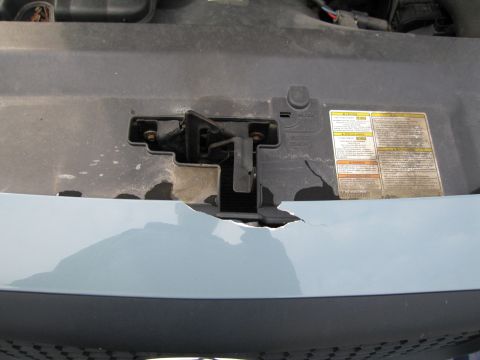 1991 Ford LTD Crown Victoria - Close-up of a damaged engine bay latch mechanism with visible warning labels.