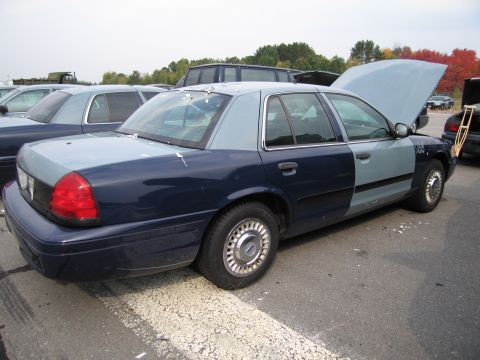 1991 Ford LTD Crown Victoria - A two-tone Ford Crown Victoria is parked with its hood open, showing damage and a crutch nearby.