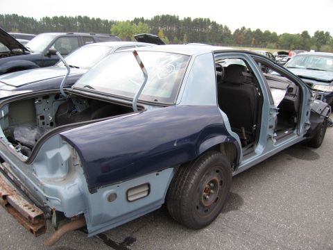 1991 Ford LTD Crown Victoria - Junkyard sedan, stripped of parts, with doors and trunk open.