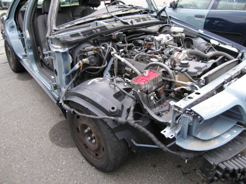 1991 Ford LTD Crown Victoria - This light blue sedan shows significant front-end damage with its engine compartment exposed.