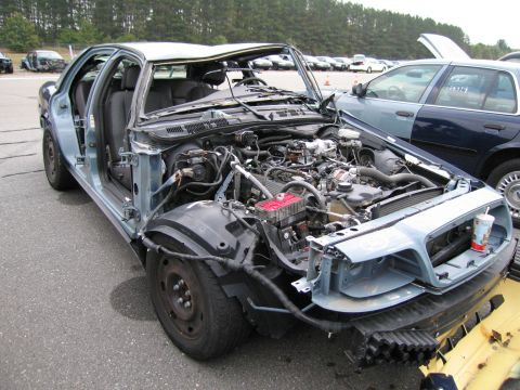 1991 Ford LTD Crown Victoria - A damaged 1991 Ford Crown Victoria LTD is shown with its hood open and engine exposed, revealing significant wear and tear.