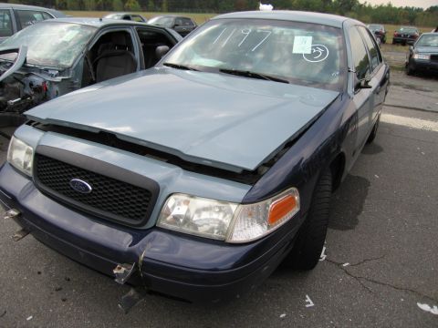 1991 Ford LTD Crown Victoria - Front view of a Ford Crown Victoria, likely from the early 2000s, with its hood ajar. Another vehicle is partially visible on the left.
