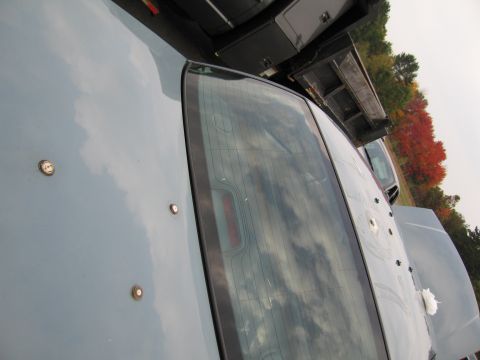 1991 Ford LTD Crown Victoria - Bullet holes are visible on the trunk and roof of a light blue car, with a dump truck behind it.