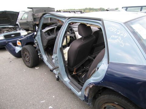 1991 Ford LTD Crown Victoria - Damaged police car interior with doors removed, parts marked on window. Another wrecked vehicle in background.