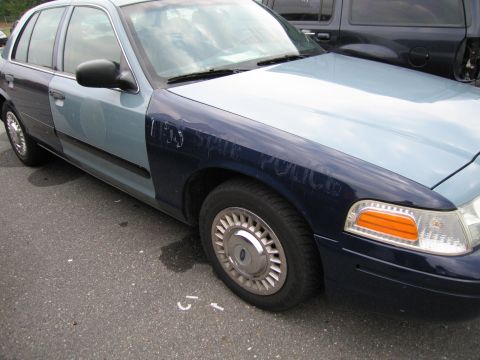 1991 Ford LTD Crown Victoria - A two-tone police car shows 'STATE POLICE' text on its dark blue fender.