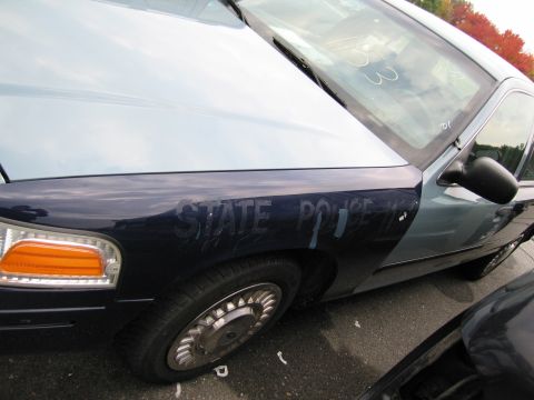1991 Ford LTD Crown Victoria - Close-up of a police car's fender shows 'STATE POLICE' markings and a partial view of another vehicle.